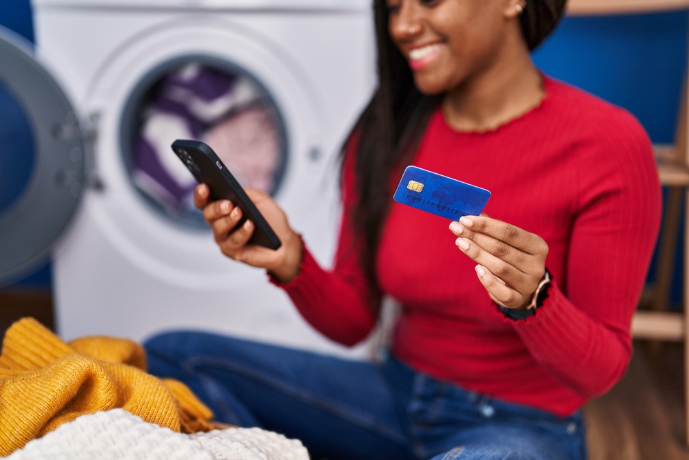 woman holding a credit card looking at her phone to place an order
